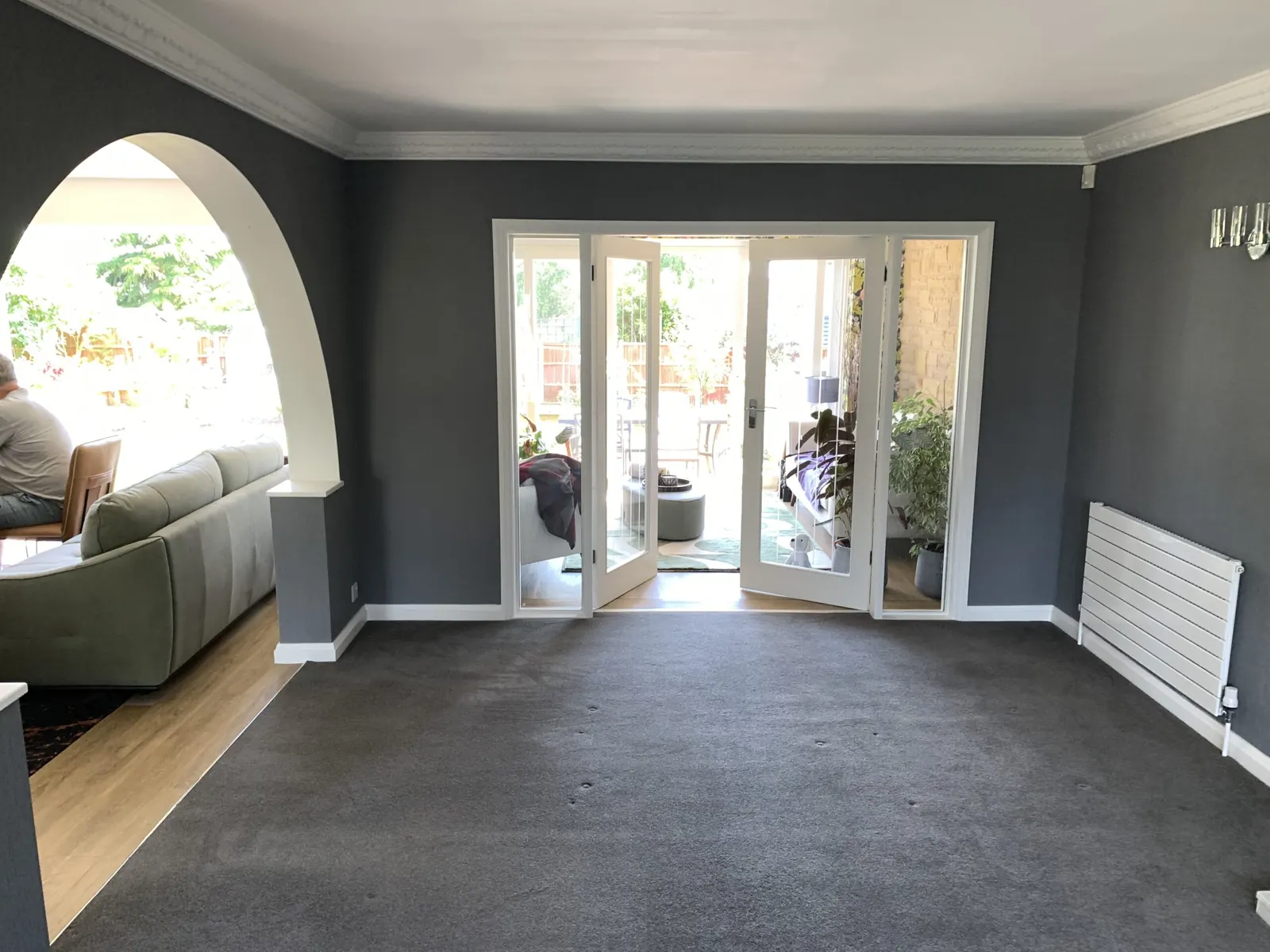 Living room with grey painted walls, an arched opening and patio doors